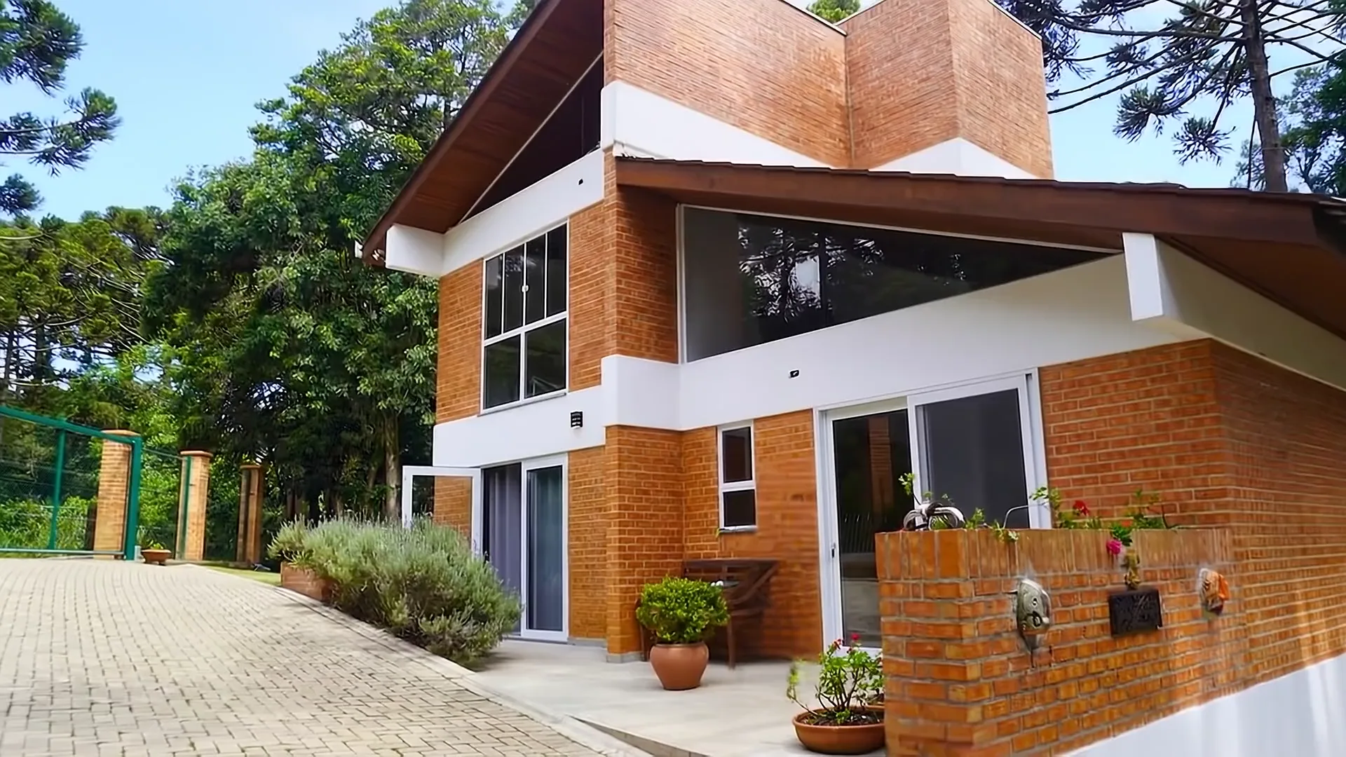 Fachada da Pousada das Strelitzias, tijolo aparente entre araucárias