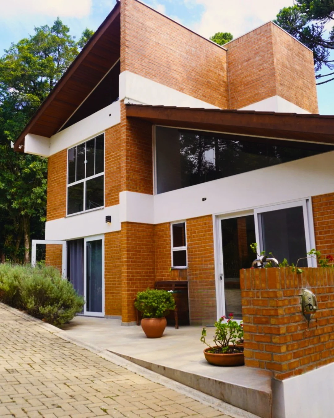 Fachada da Pousada das Strelitzias, tijolo aparente entre araucárias